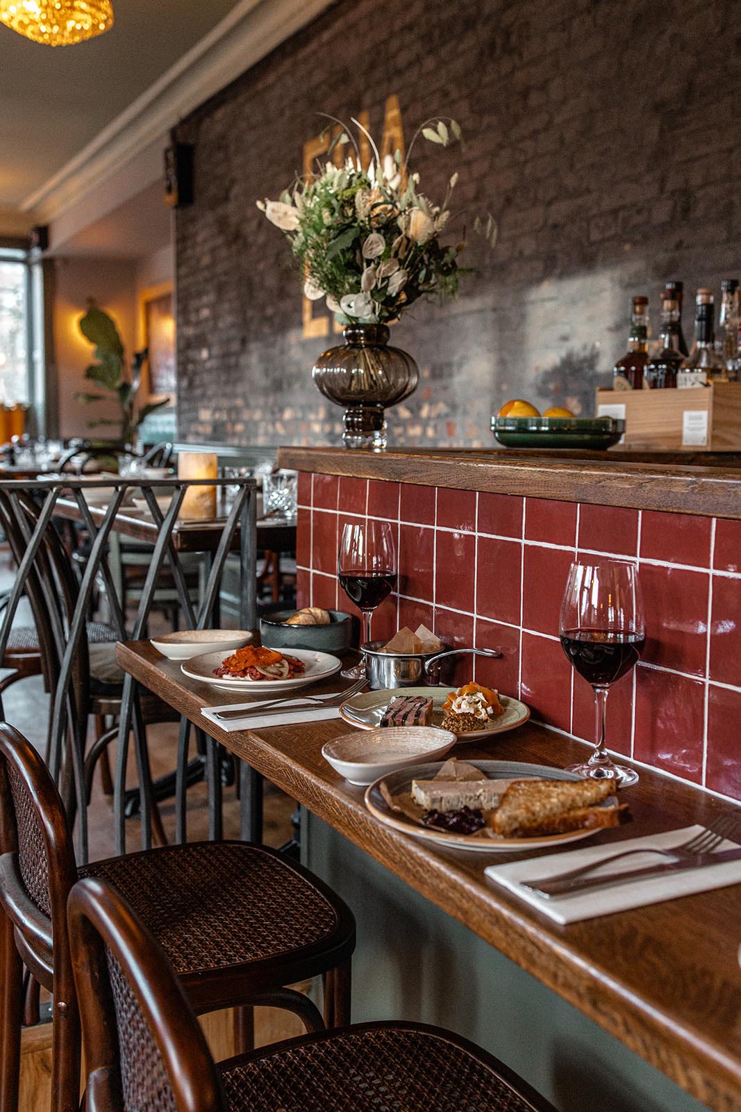 Auf dem Bartresen eines ansprechend eingerichteten Restaurants steht ein grün-weißer Blumenstrauß in einer bauchigen Vase