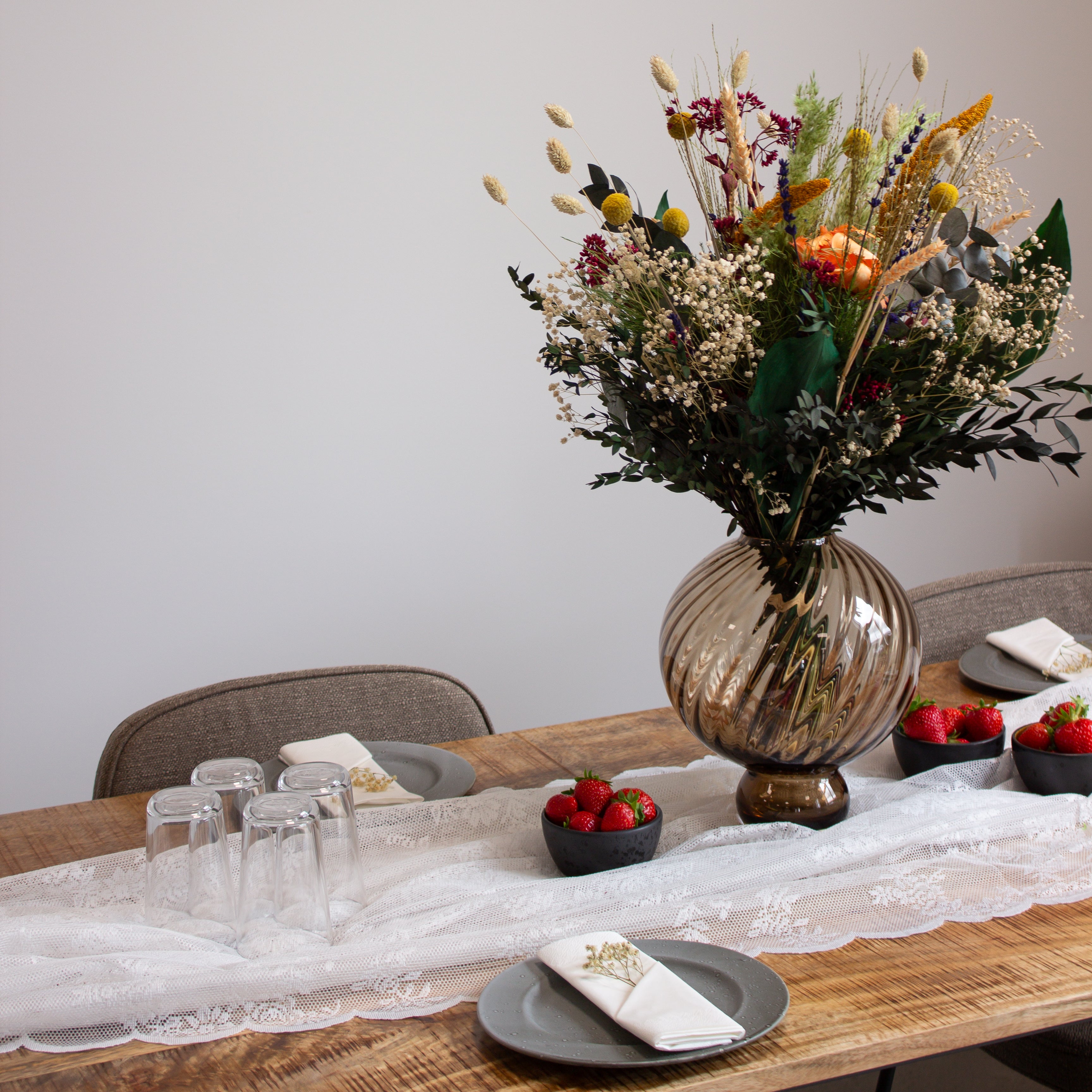 Ein langlebiger BlumenstrauBlumenstrauß  in warmen Tönen, der auf einem gedeckten Tisch steht.