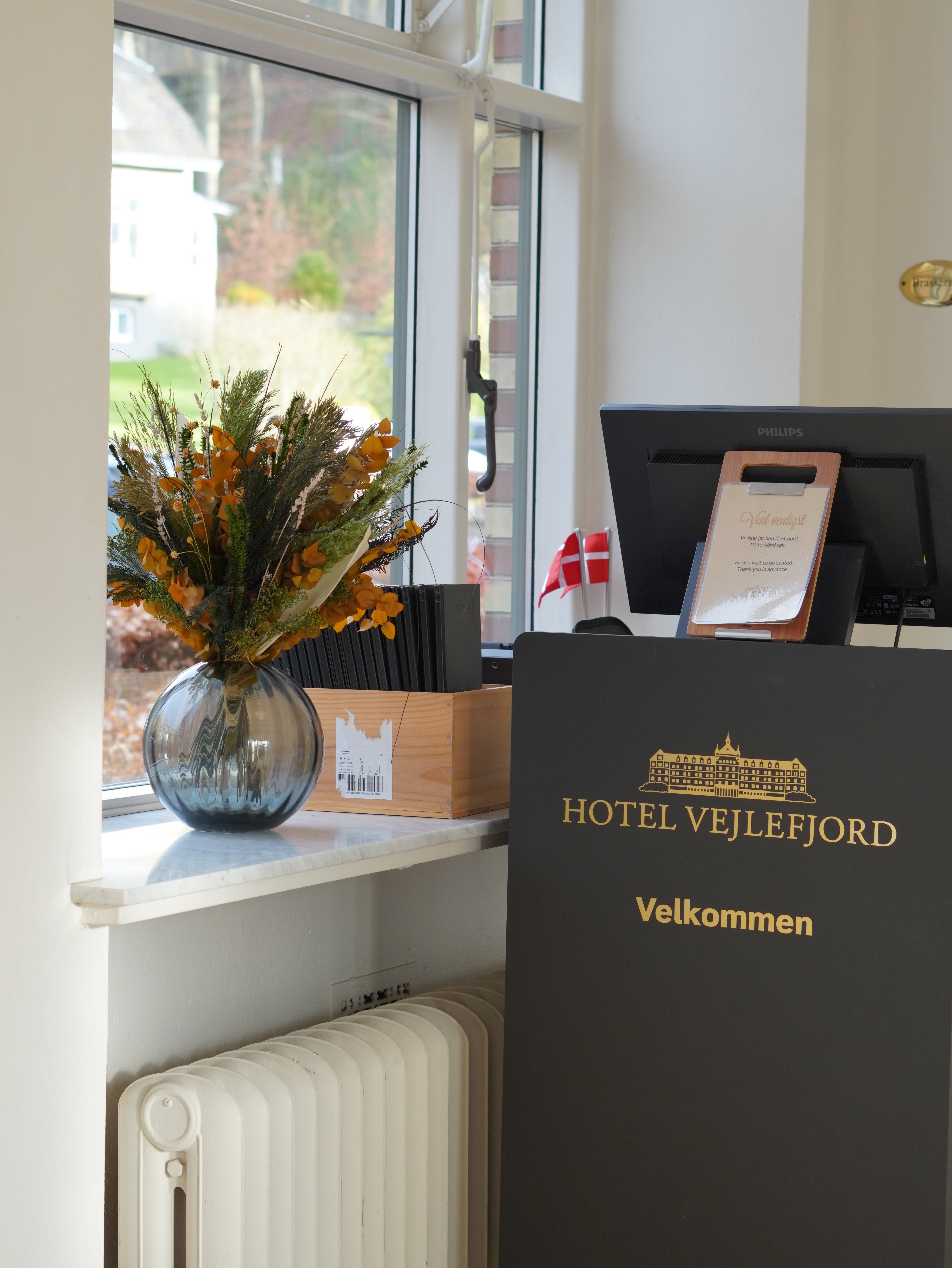 Auf der Fensterbank im Empfangsbereich des Hotels steht ein Blumenstrauß in warmen Herbsttönen