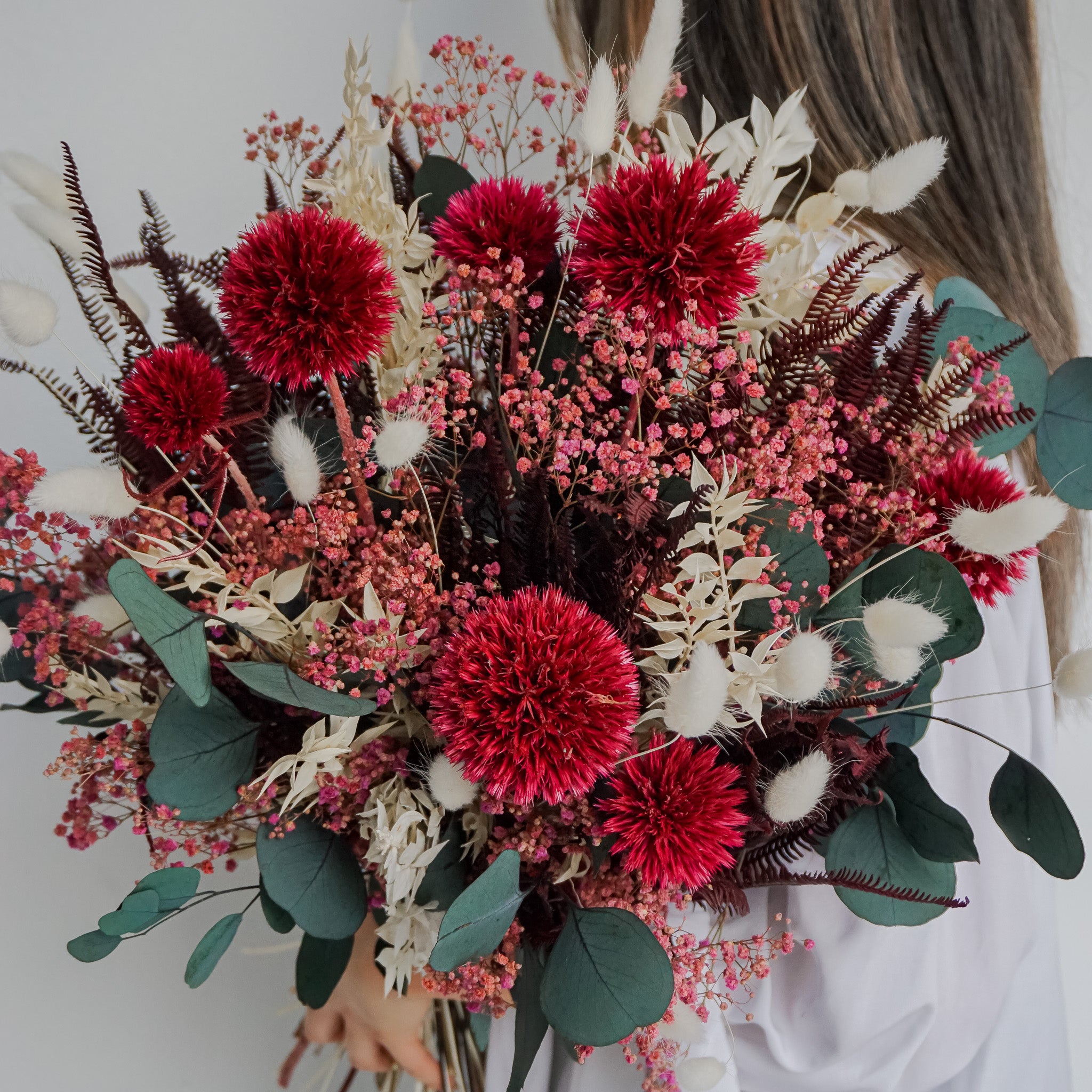Eine Frau hält einen langlebigen Blumenstrauß in roten-weißen Nuancen in die Kamera
