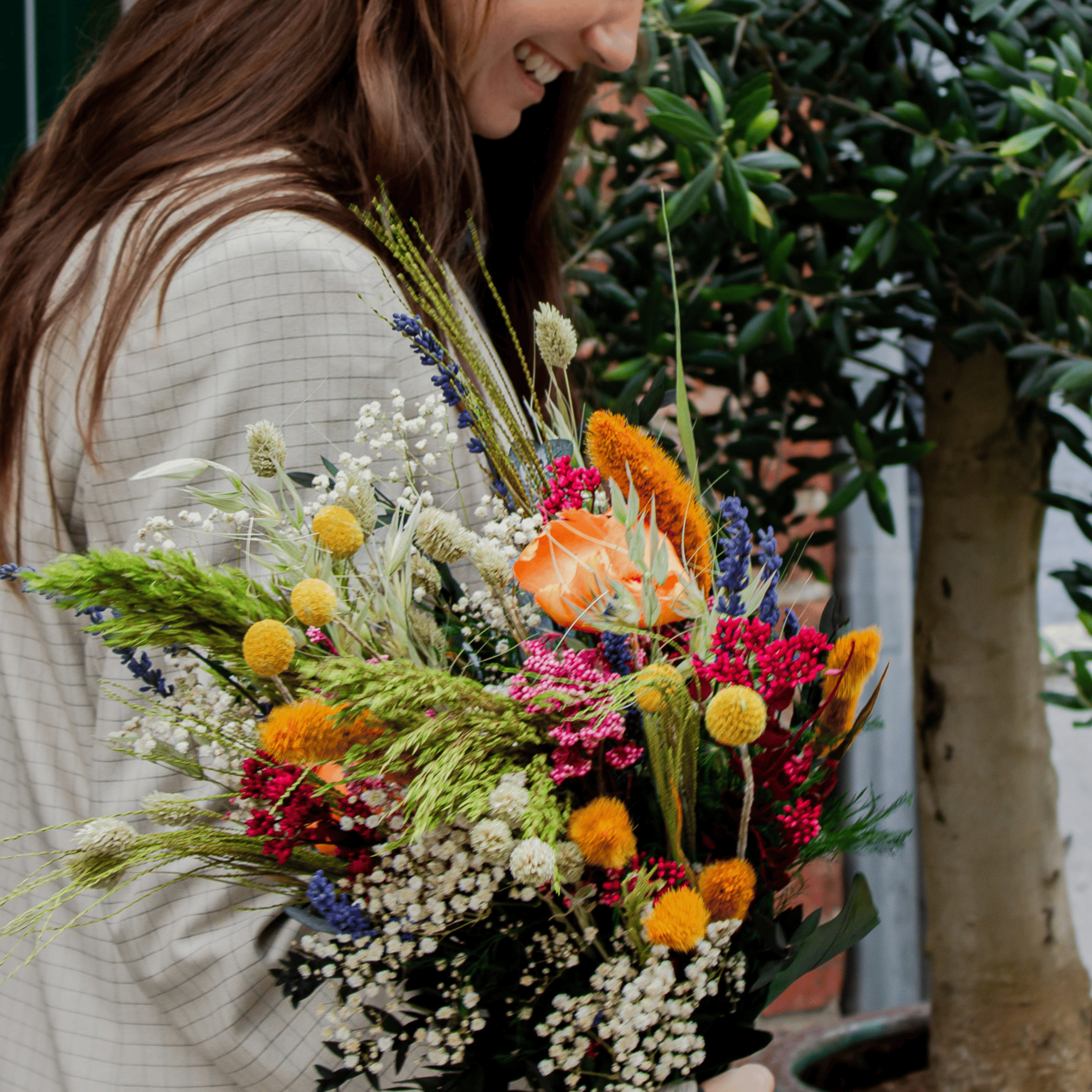 Eine lächelnde Frau hält einen bunten Blumenstrauß in der Hand