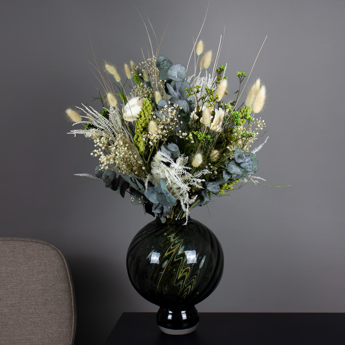 In einer bauchigen Vase steht ein natürlicher Blumenstrauß mit vielen grünen Akzenten