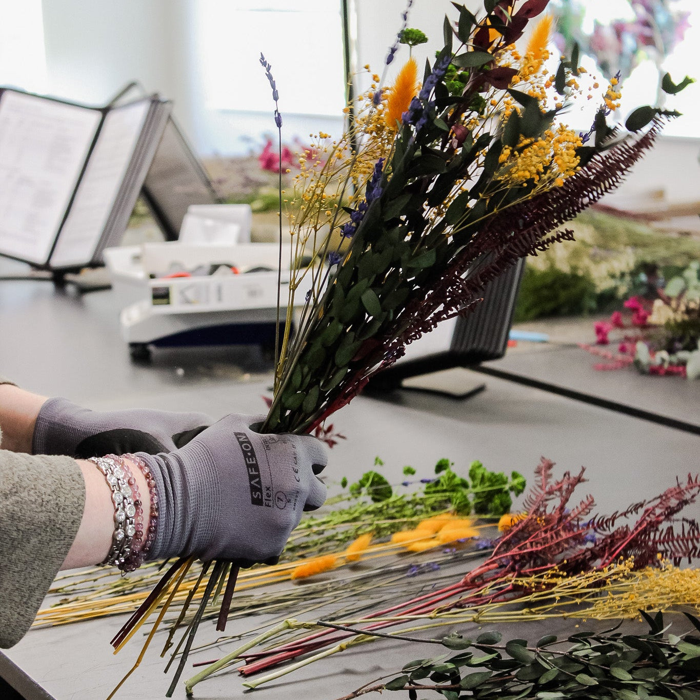 Eine Floristin bindet einen Blumenstrauß aus langlebigen Blumen in warmen Farben
