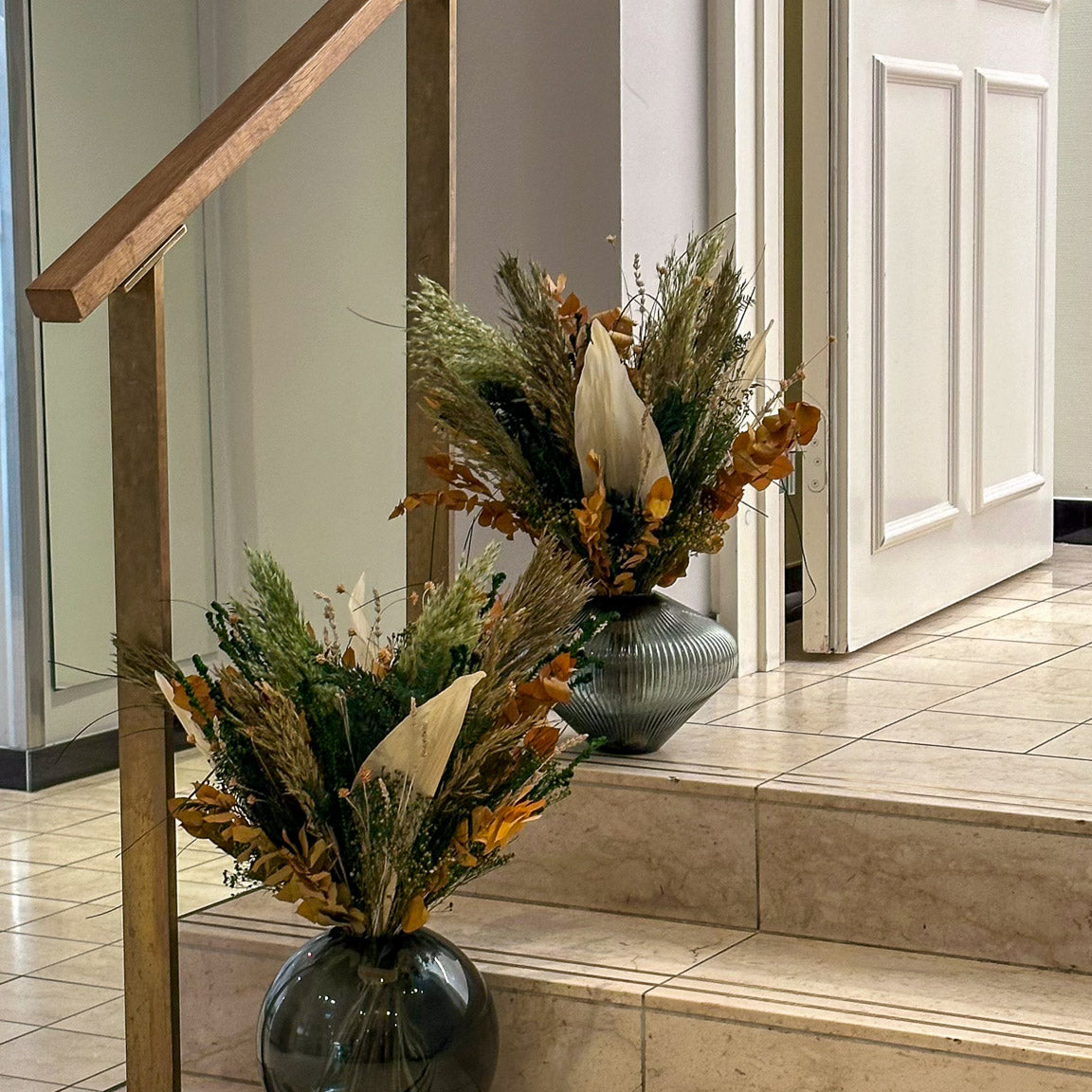 Auf den Treppenabsätzen im Hotel stehen zwei Blumensträuße in herbstlichen Farben