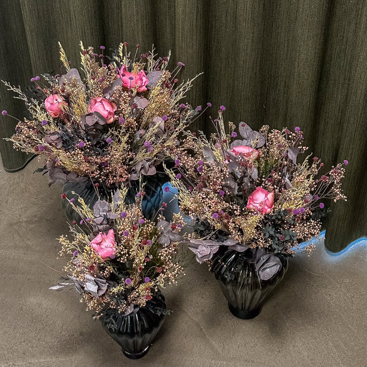 Drei unterschiedlich große, langlebige Blumensträuße stehen in Glasvasen auf dem Boden