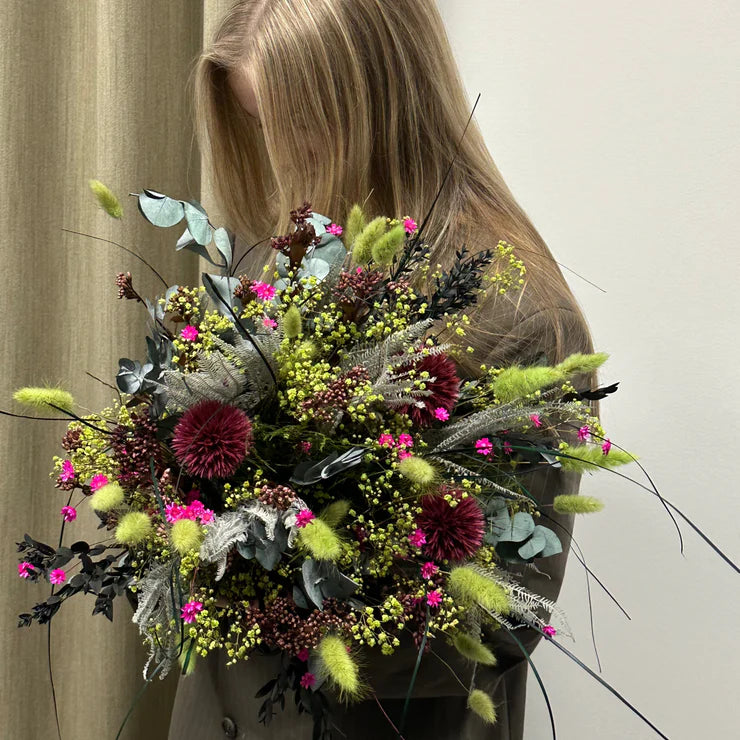 Ein Mädchen hält einen grün-rosa Blumenstrauß.