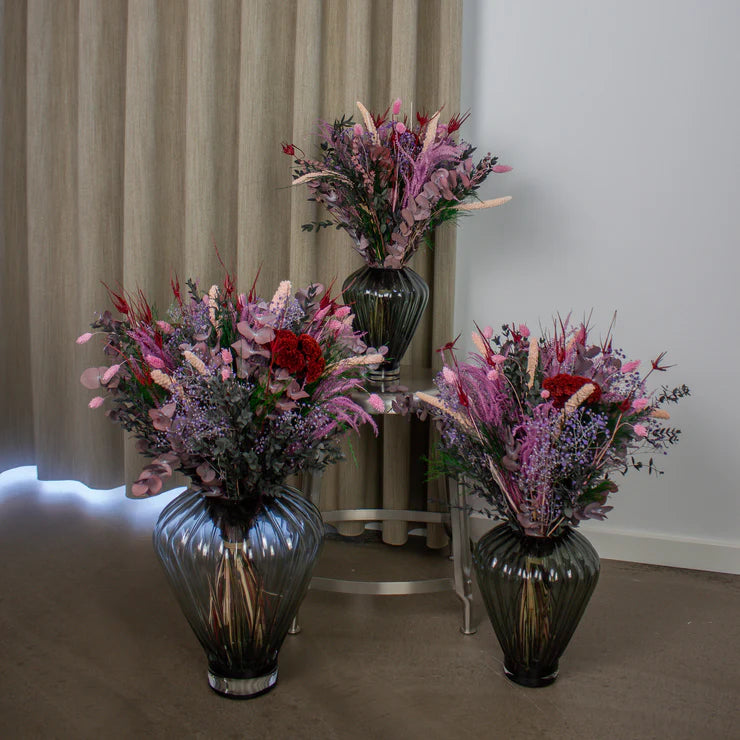 Drei Blumensträuße in unterschiedlichen Größen stehen in geriffelten Glasvasen, deren Größe auf die Größe der Sträuße ngepasst ist.