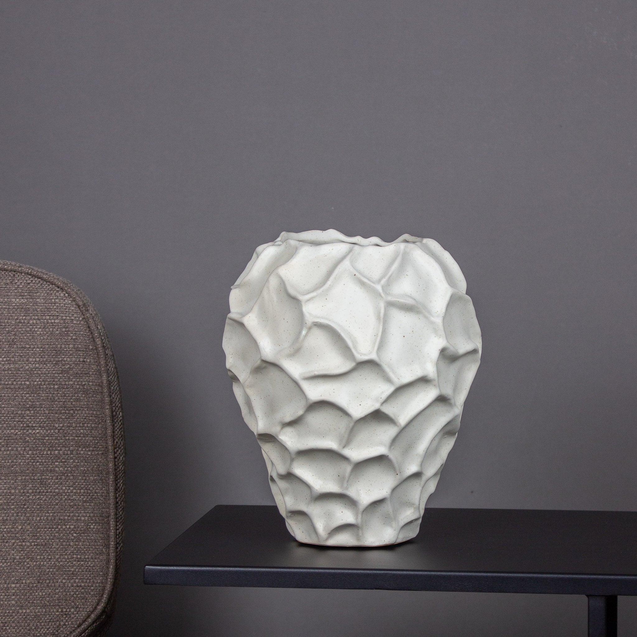 Auf einem Tisch steht eine Keramikvase mit auffälliger Struktur