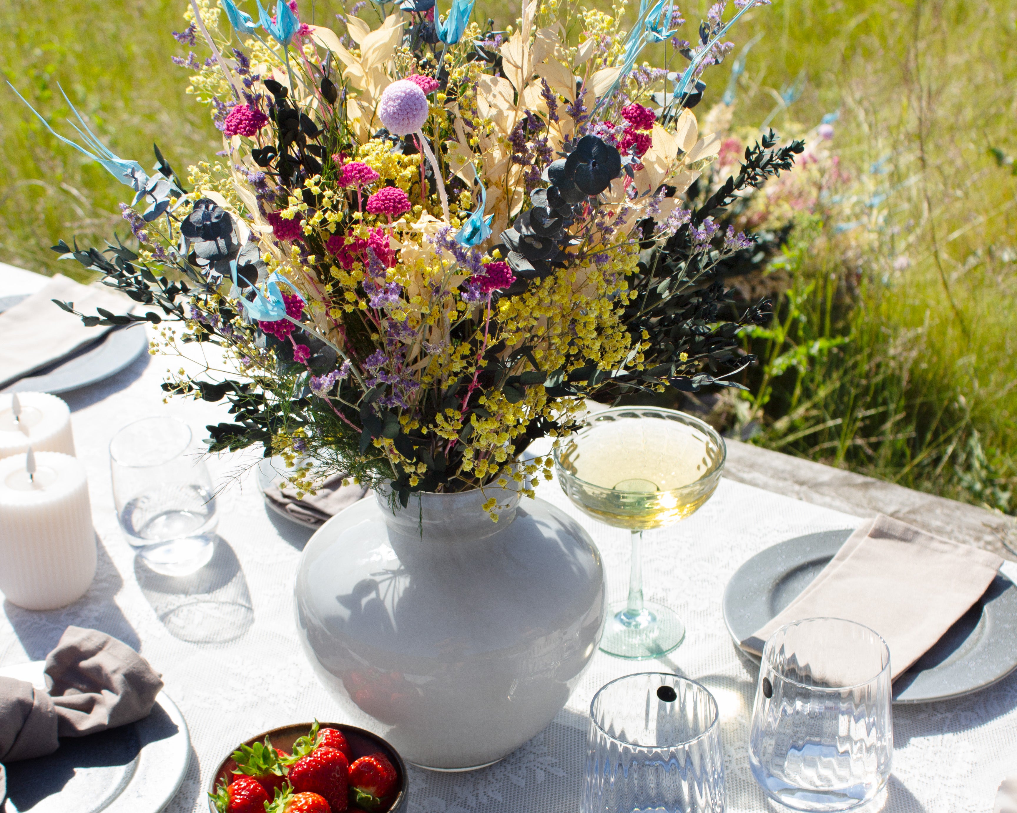 Blumenstrauß in zarten Pastelltönen, der inmitten einer sommerlich gedeckten Tafel steht