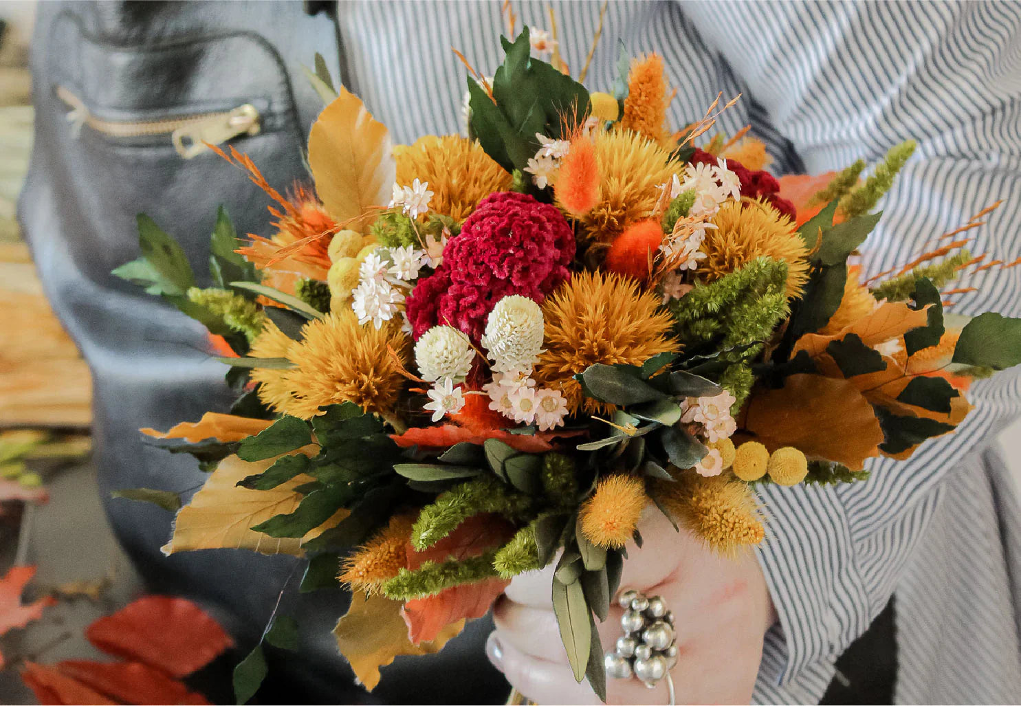 Eine Frau hält einen kleinen Blumenstrauß in herbstlichen orangen und roten Tönen