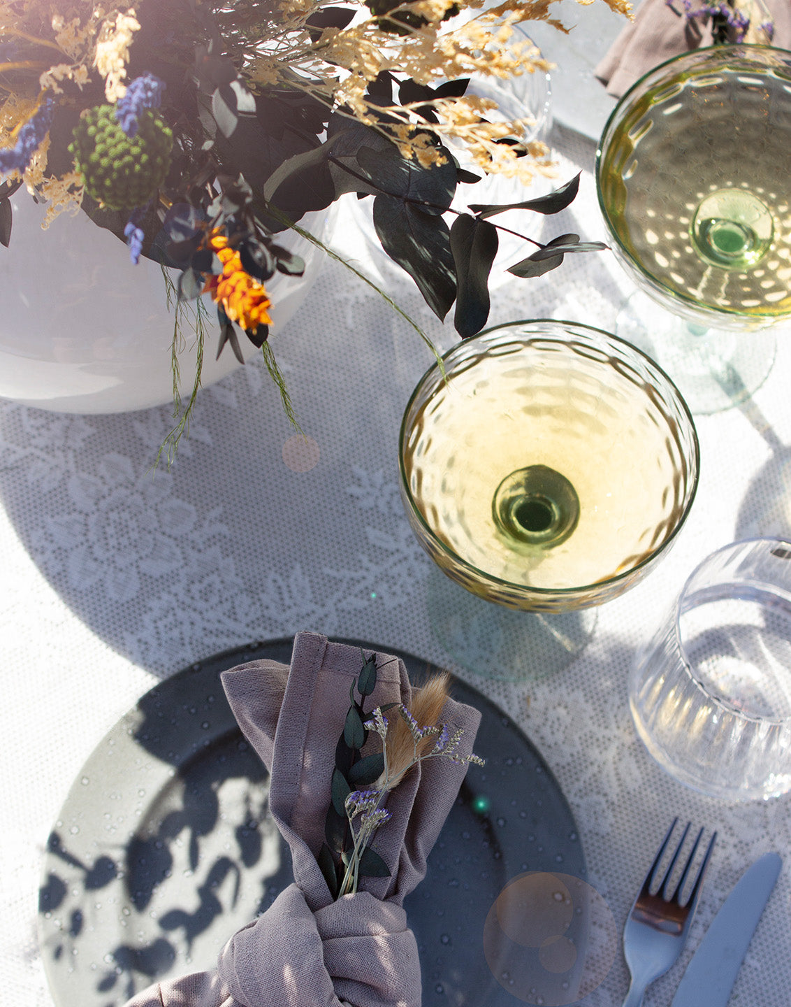 Ein sommerlich gedeckter Tisch in natürlichen Farben, auf dem ein farbenfroher langlebiger Blumenstrauß steht