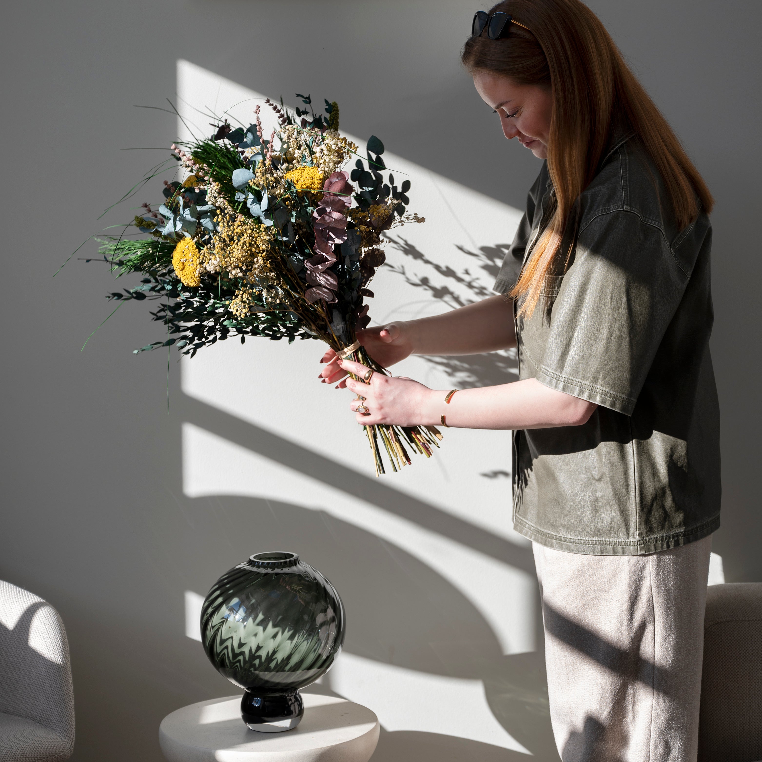 Frau hält blumenstrauss mit grossen gelben blumen und grünen elementen 