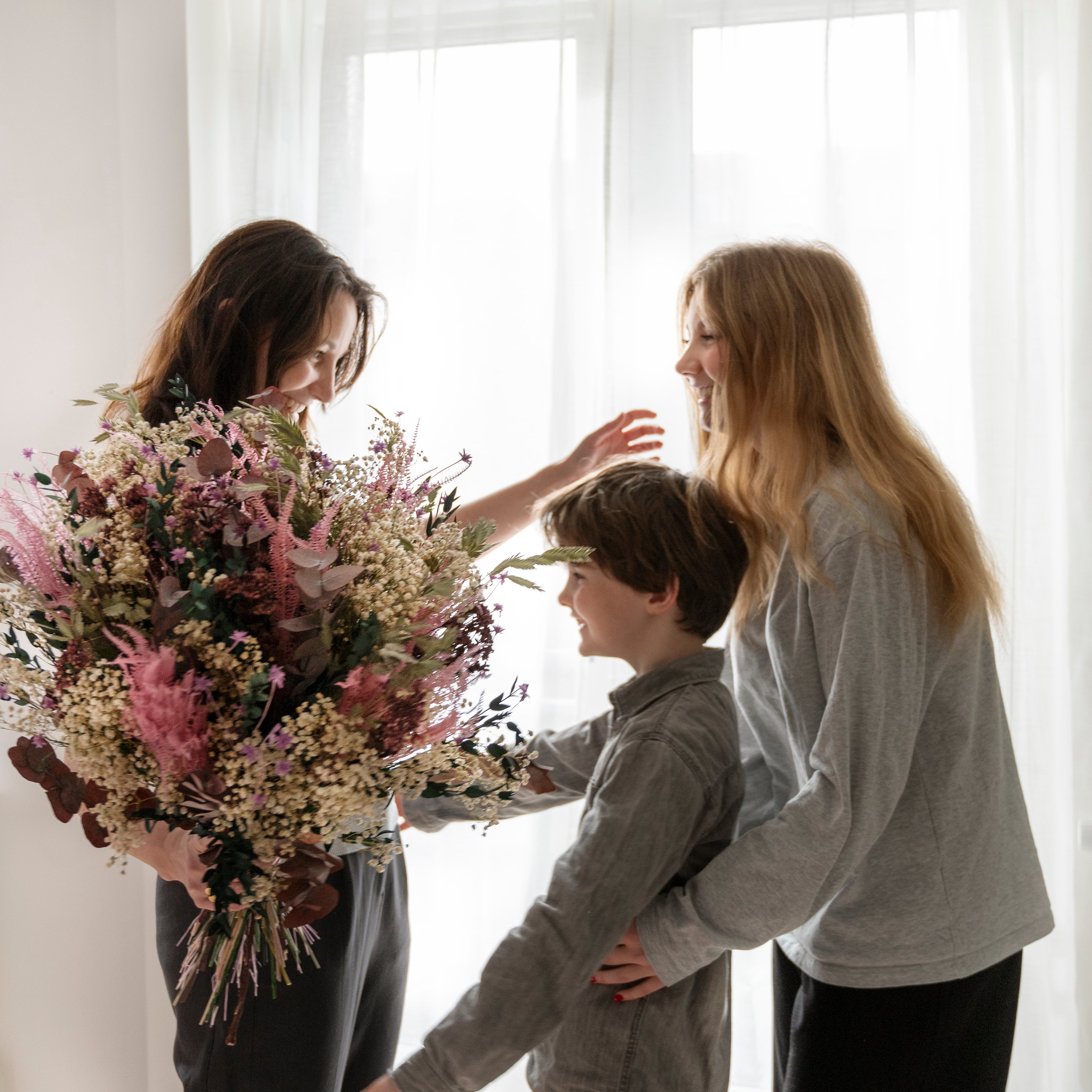 Kinder überraschen ihre Mutter mit einem großen Living Flowers Blumenstrauß zum Muttertag.