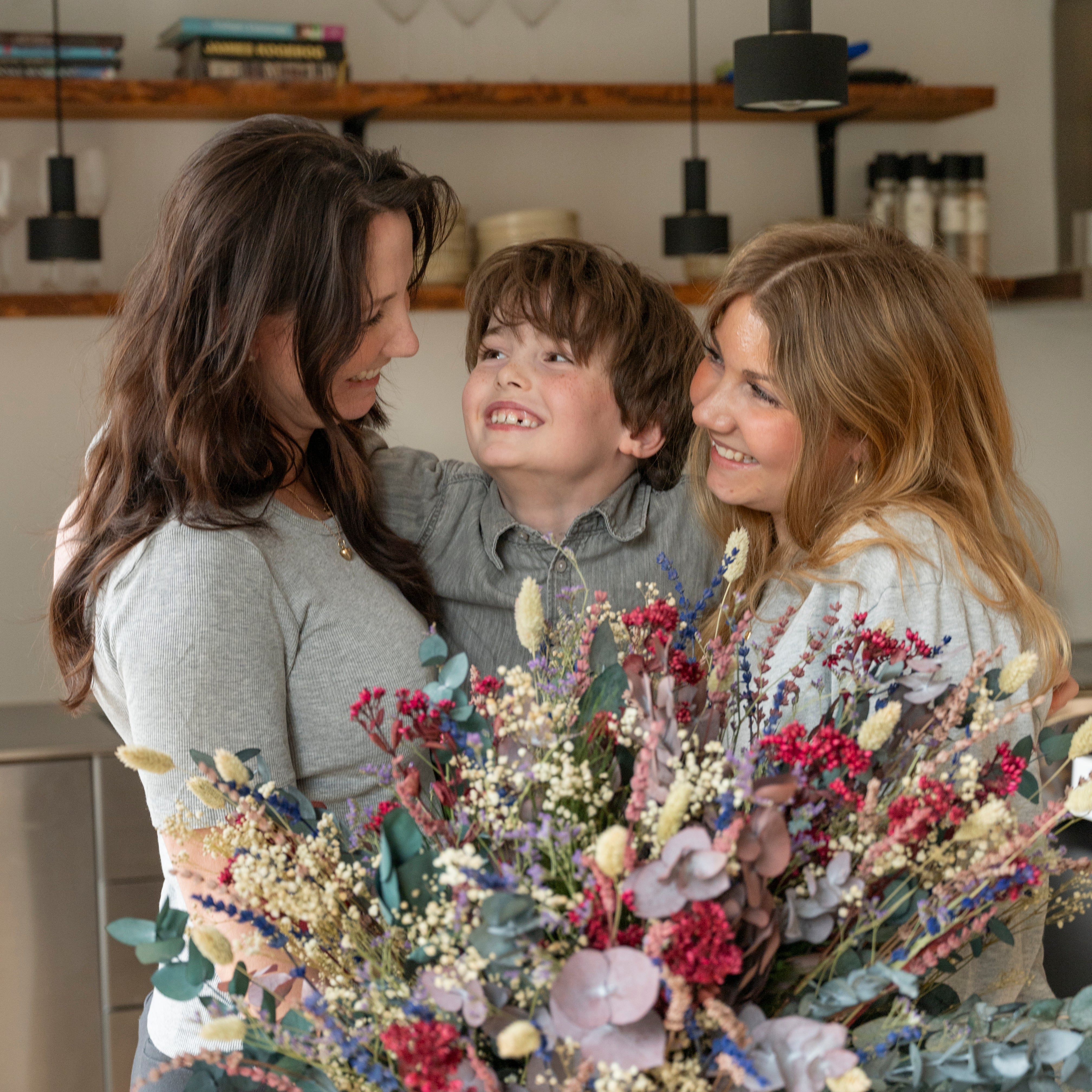 Familie freut sich über den Living Flowers Strauß Frische Brise mit bunten Trockenblumen und Eukalyptus