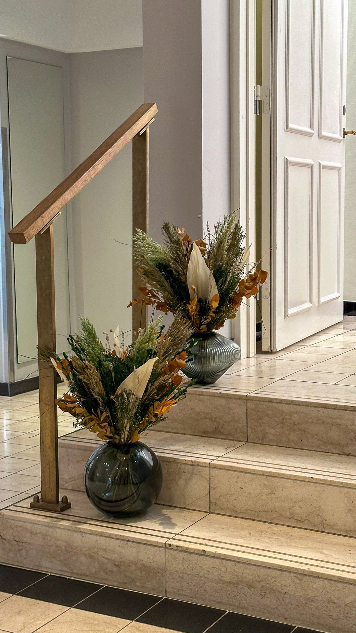 Auf den Treppenabsätzen im Hotel stehen zwei Blumensträuße in herbstlichen Farben