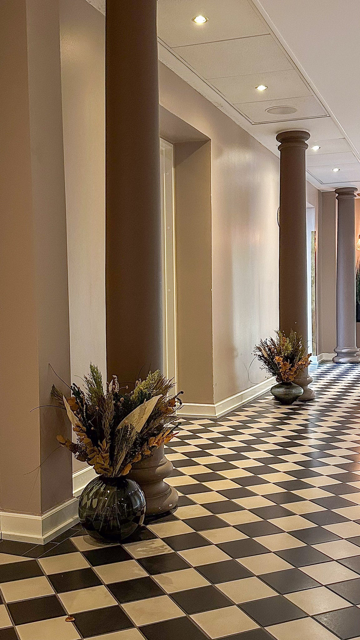 In den Aufenthaltsbereichen des Hotels stehen eindrucksvolle große Vasen mit Blumensträußen in warmen Tönen