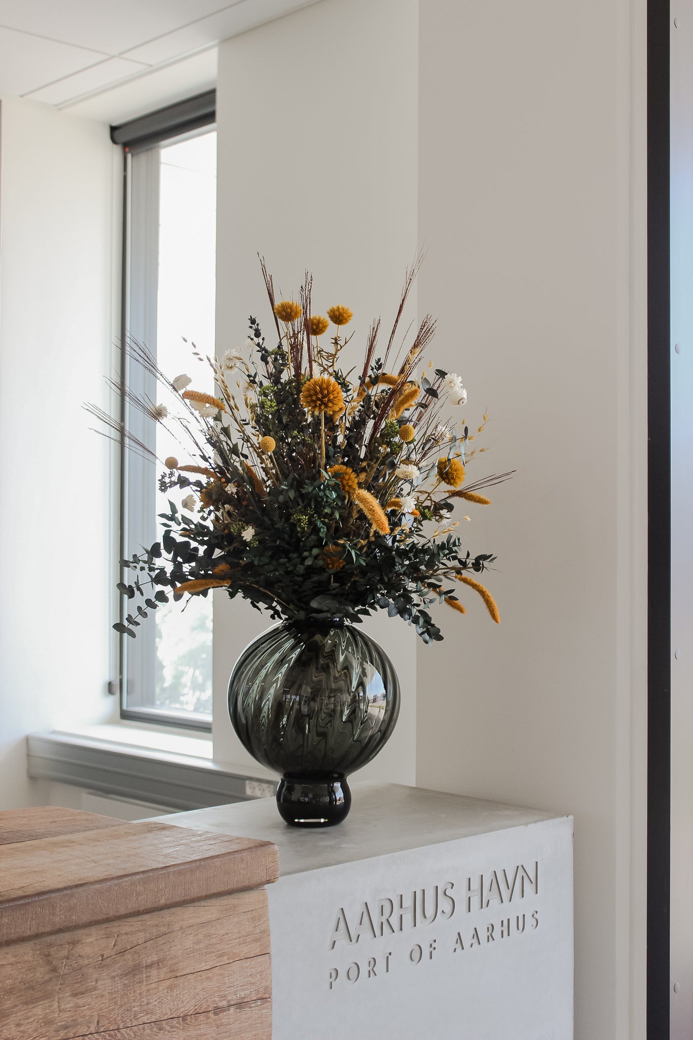 Auf dem Empfangstresen eines Unternehmens steht ein Blumenstrauß in warmen Herbstfarben