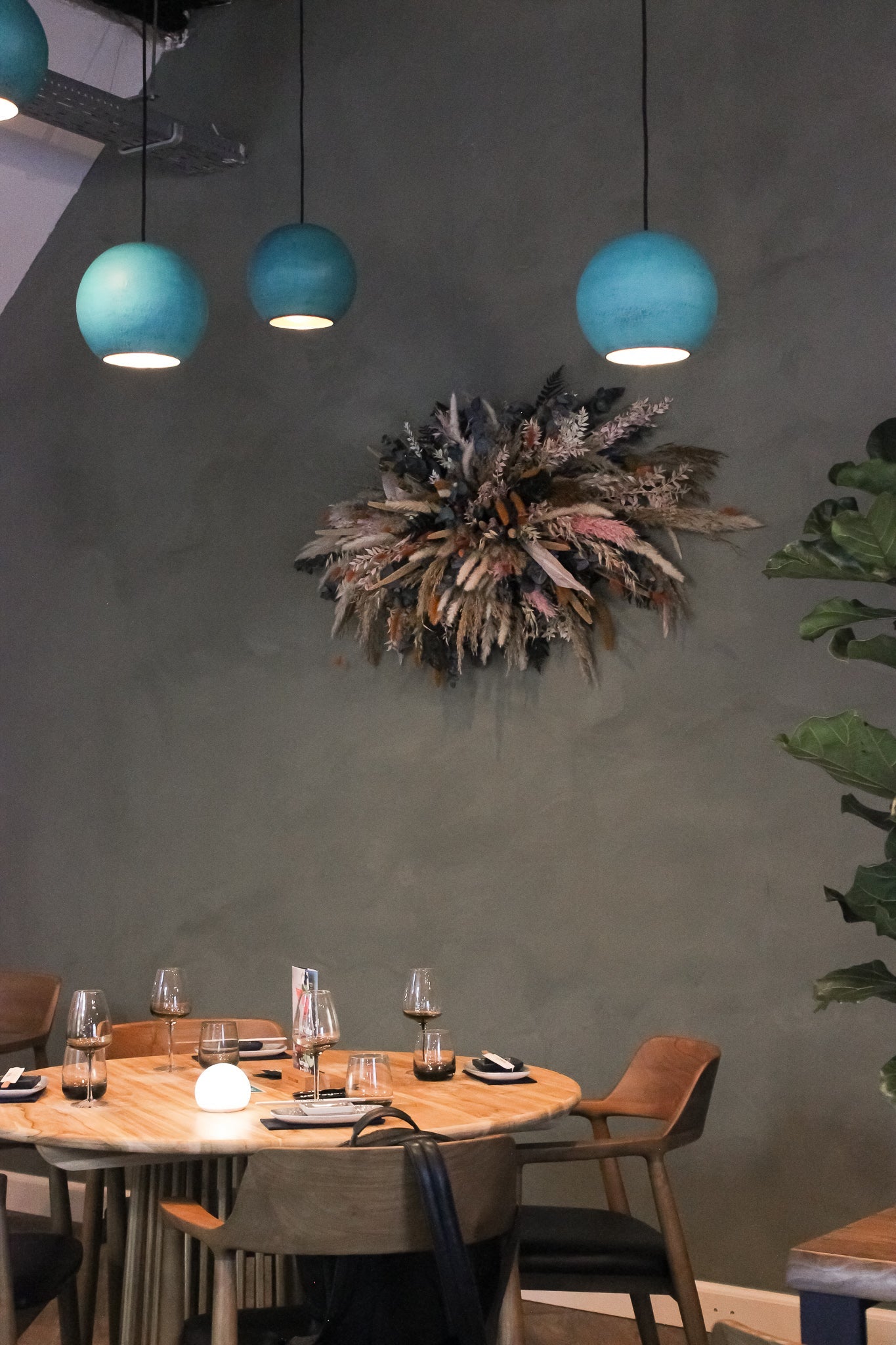 An der Wand neben einem gedeckten Tisch hängt ein auffälliges Blumenarrangement