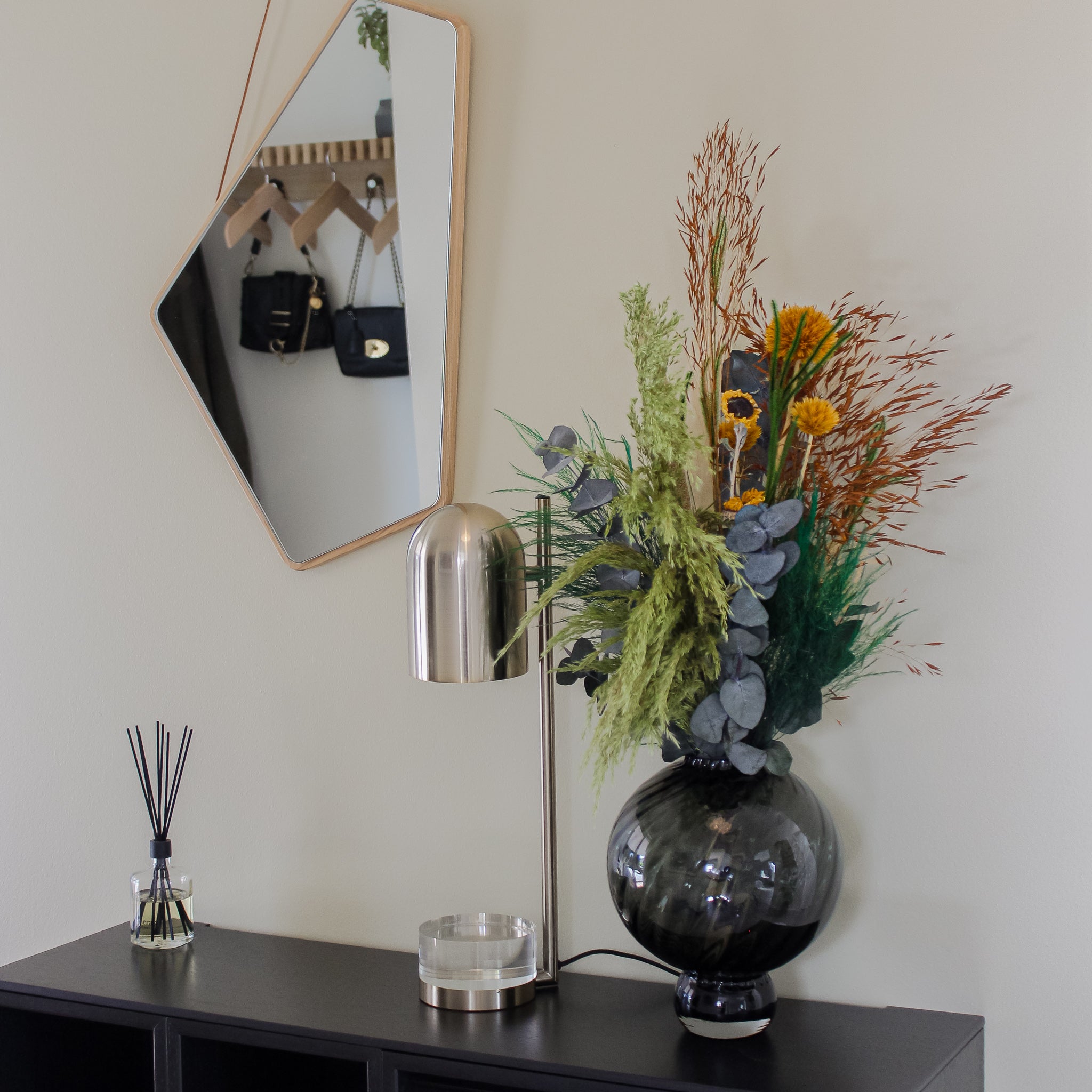 Auf einem Sideboard in einem Flur steht ein Blumenstrauss in warmen Herbstfarben.