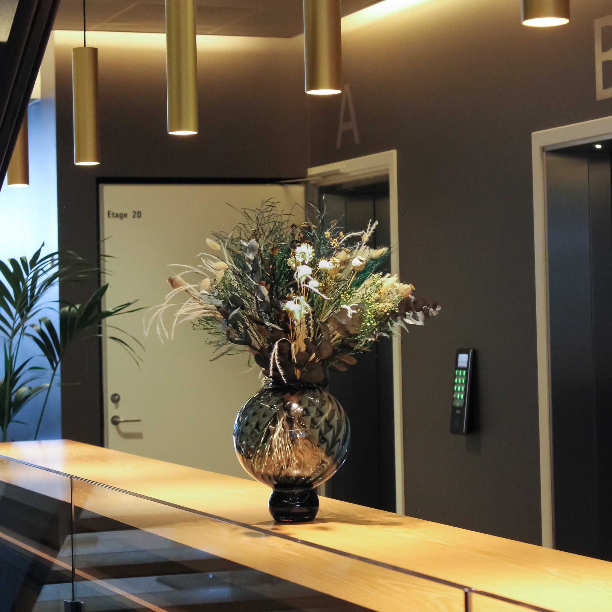 Auf einem Sideboard in dem Flur eines Unternehmens steht ein eindrucksvoller Blumenstrauß 