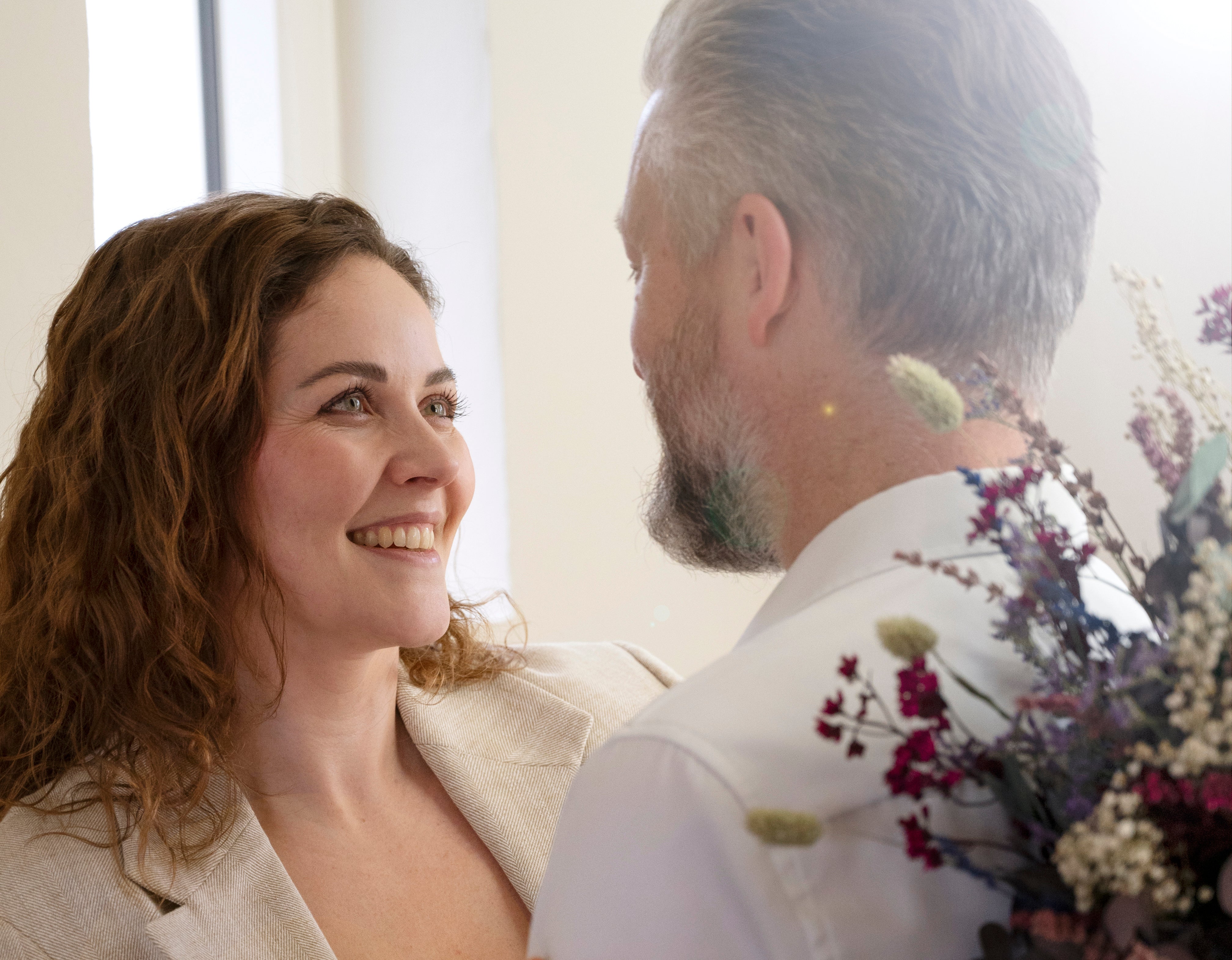 Lächelnde Frau und Mann mit einem Living Flowers Blumenstrauß in lila, rosa und weißen Tönen